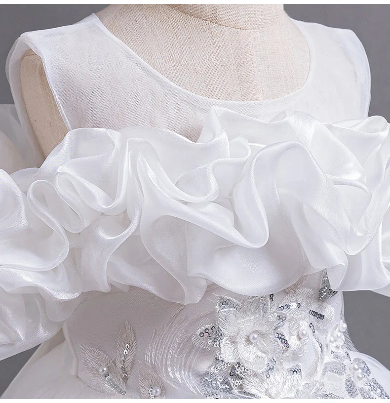 Close-up of delicate pearl decorations on a luxurious embroidered mesh evening gown for girls, ideal for formal events.