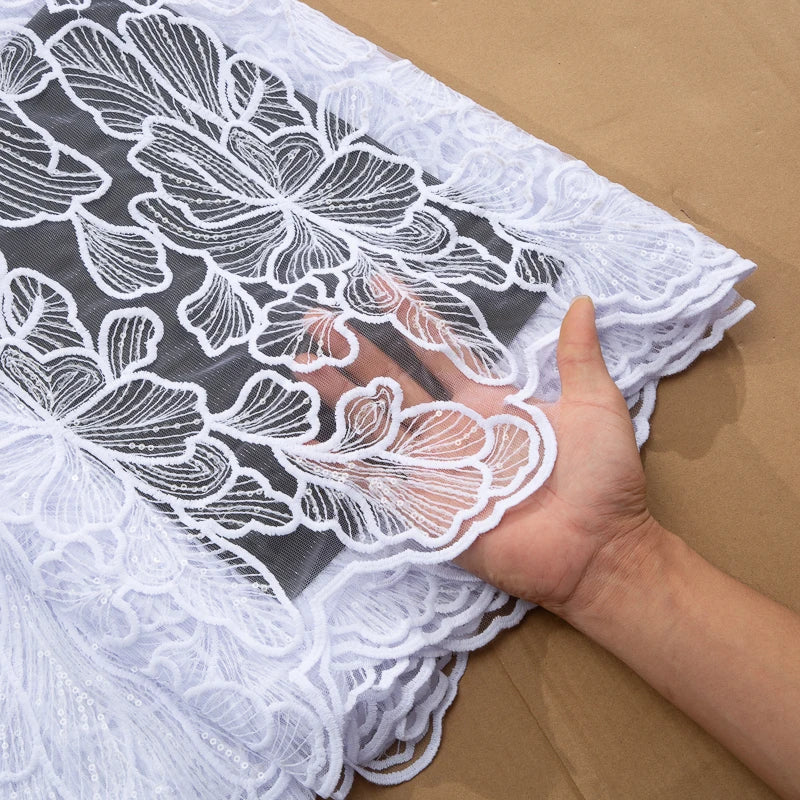 Elegant African Milk Silk Mesh Lace Fabric adorned with sequins, ideal for bespoke Nigerian wedding dresses, showcasing intricate embroidery on soft tulle.