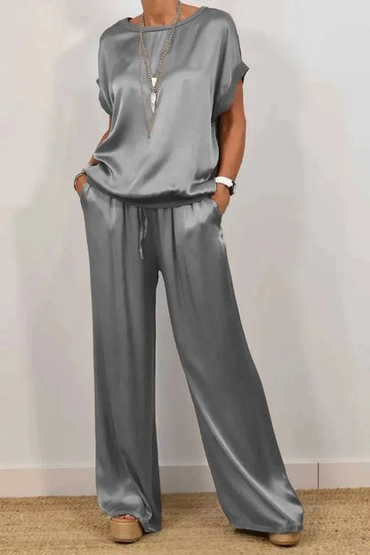 Model gracefully wearing a luxury loose satin t-shirt and wide leg pant set, exemplifying chic summer elegance.