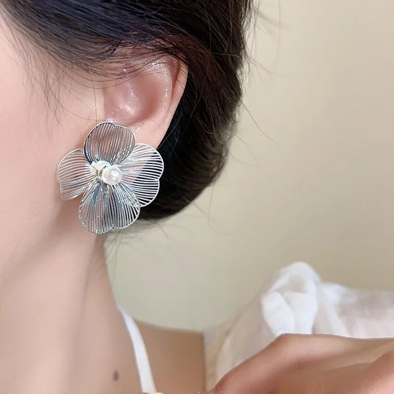 Close-up view of luxurious drop earrings featuring intricate flower petal design and shimmering imitation pearls, showcasing trendy fashion jewellery for women.