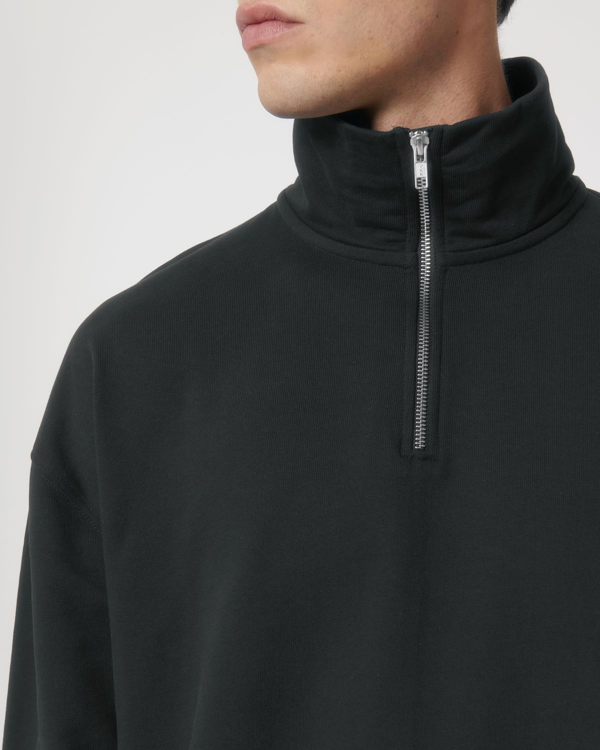 Detailed view of the quarter zip design of the unisex organic sweatshirt, highlighting its modern aesthetic and premium material.