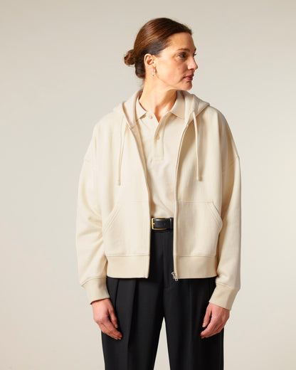 Full-length image of a woman in a medium fit organic cotton hoodie, demonstrating its flattering adjusted length and set-in sleeve design.