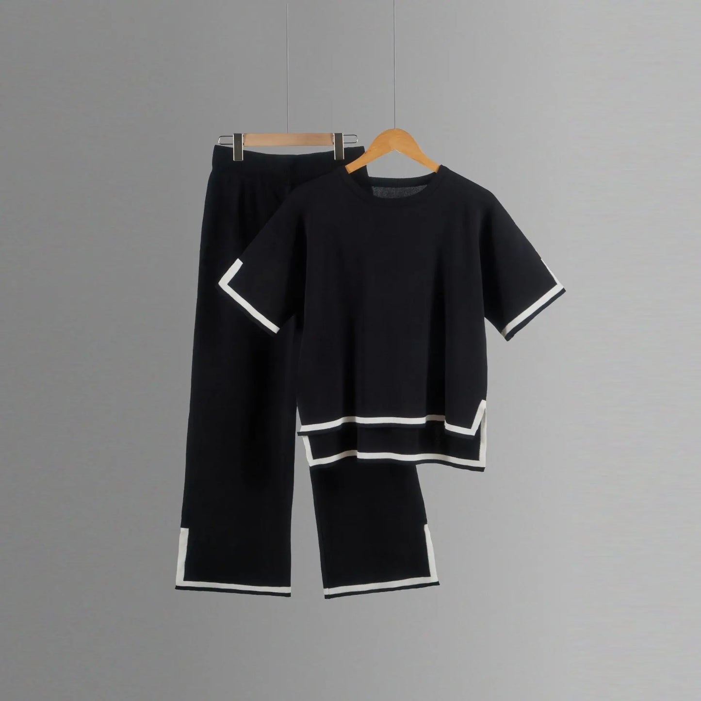 Lifestyle shot of a woman wearing an elegant knitted trousers suit, highlighting the stylish wide-leg design and chic short-sleeved pullover.