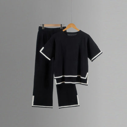 Lifestyle shot of a woman wearing an elegant knitted trousers suit, highlighting the stylish wide-leg design and chic short-sleeved pullover.