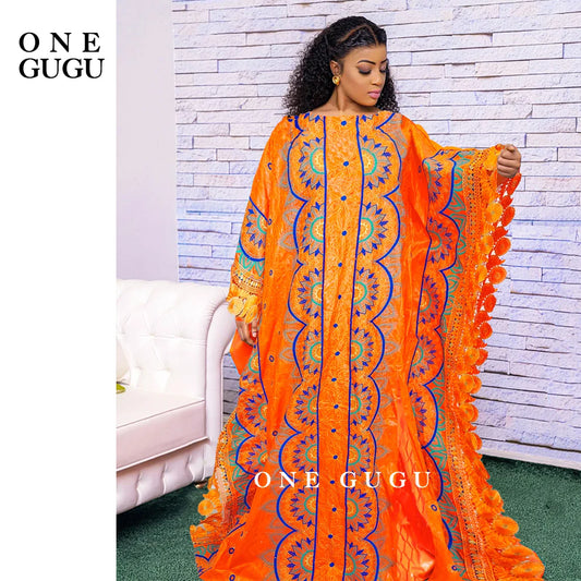 Luxurious orange Nigerian Bazin dress featuring intricate embroidery lace, ideal for elegant weddings and parties.