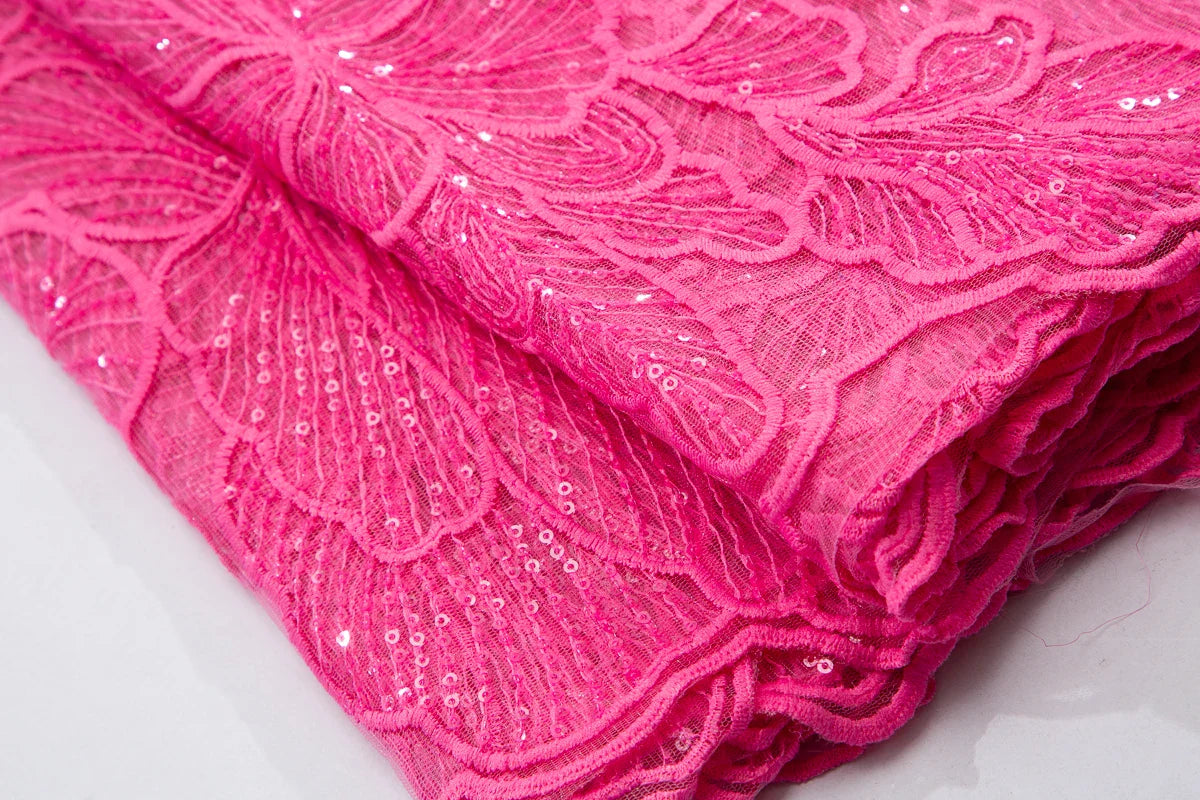 Close-up detail of exquisite embroidered lace fabric featuring shimmering sequins, ideal for upscale bridal wear and special occasions.