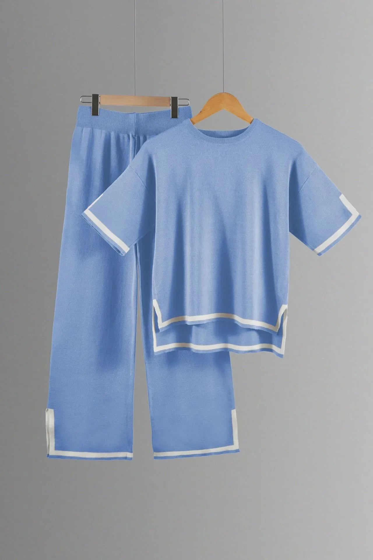 Stylish model showcasing a two-piece knitted trousers suit with wide-leg pants and a chic short-sleeved pullover, perfect for upscale casual occasions.