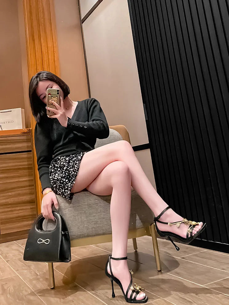 Close-up of stylish black high heel sandals showcasing the intricate gold flower metal design, ideal for women seeking fashionable footwear.