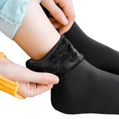 Luxury Women's Velvet Thermal Socks: Close-up of hands putting on classic black thermal socks, highlighting the soft velvet texture.