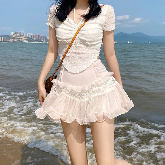 Model wearing a Sweet Pink Ruffle A-Line Skirt with Lace Patchwork by Dazzling Dreams Studio while standing by the seaside, accentuating the skirt’s romantic aesthetics and flowing silhouette.