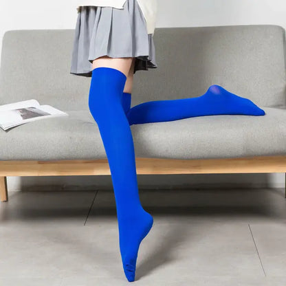 Women's Black White Solid Color Long Socks Stockings in rich blue, beautifully worn by a model seated on a contemporary sofa, designed to elevate any ensemble with a touch of elegance.