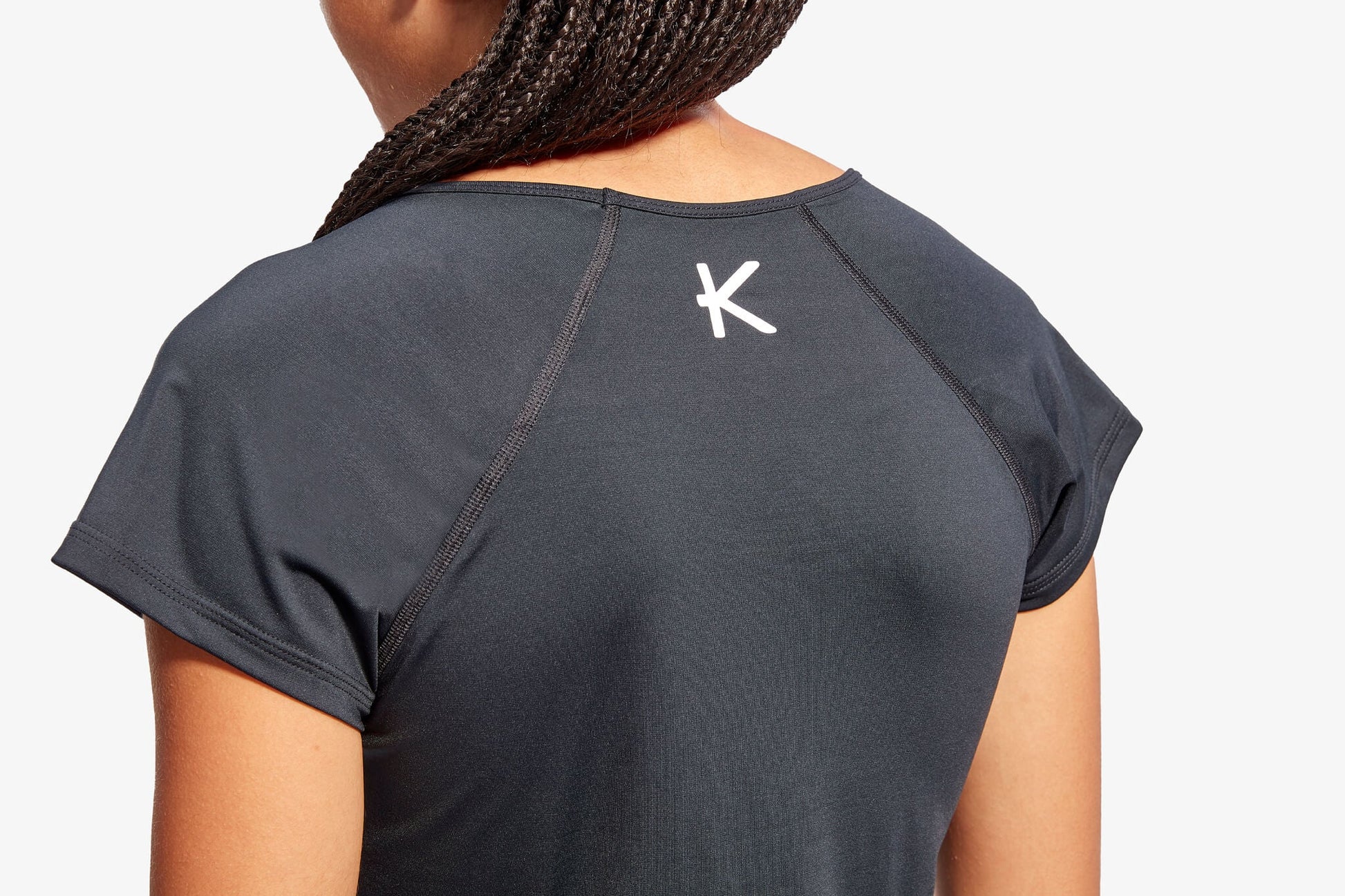 Stylish model wearing the KYMIRA women's cap sleeve top during a workout, highlighting the athletic silhouette and performance-enhancing features of the garment.