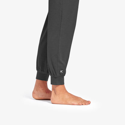 Model wearing KYMIRA Women's Infrared Recovery Sleepwear Bottoms, demonstrating stylish cuffed jogger fit and luxurious design in various sizes.