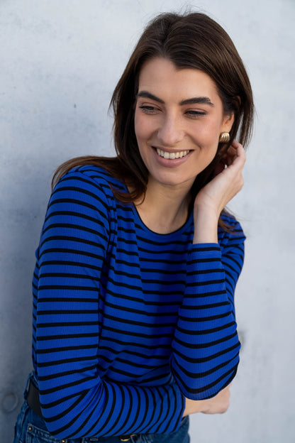 Model wearing a women's striped crew neck t-shirt in organic cotton, demonstrating versatility styled with tailored trousers for a chic look.