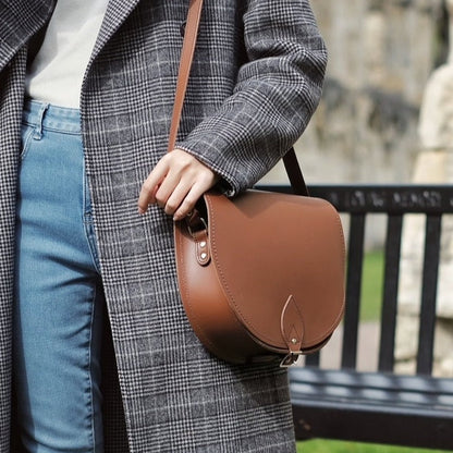 Versatile Handmade Chestnut Leather Saddle Bag modelled for both casual and formal occasions, emphasizing its adjustable crossbody strap and elegant design.