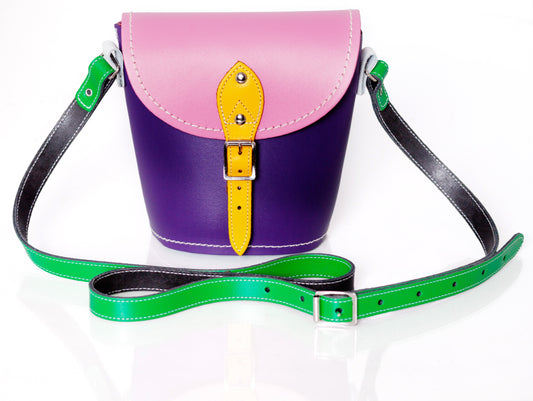 Handmade multicoloured leather barrel bag by Zatchels showcasing a vibrant kaleidoscope of colours including Pastel Pink, Pastel Daffodil Yellow, Classic Green, Red, Purple, and White, with an adjustable strap and traditional buckle fastening, perfect for stylish and functional accessory needs.