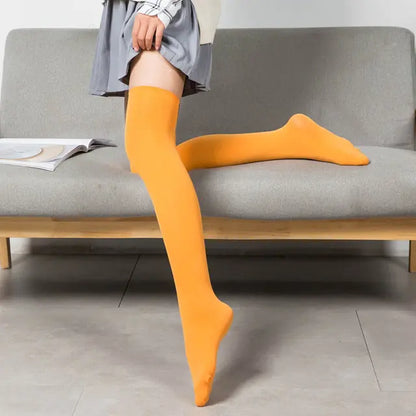 Women's Black White Solid Color Long Socks Stockings in vibrant orange, elegantly showcased on a model sitting on a stylish sofa, perfect for adding a pop of colour to any outfit.