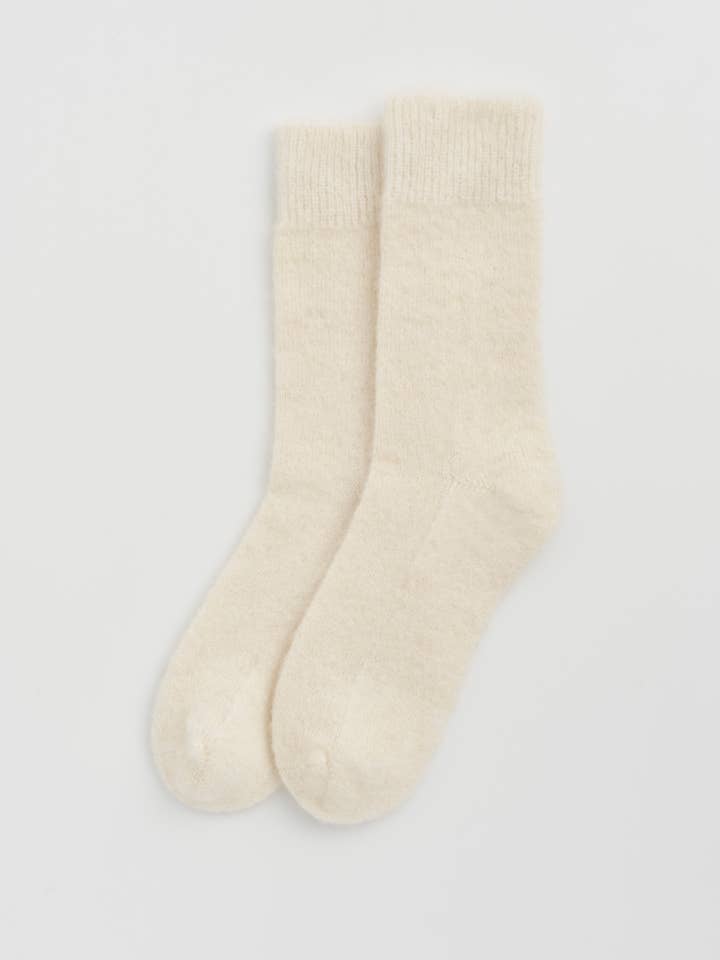 Chic display of one size fits most alpaca bed socks, emphasizing their elegant design and ultimate snugness for indoor relaxation.