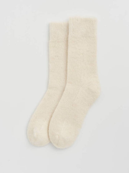 Chic display of one size fits most alpaca bed socks, emphasizing their elegant design and ultimate snugness for indoor relaxation.
