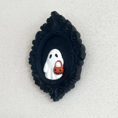 Halloween Resin Ornaments Trick Or Treat Ghost Wall Decoration with a delightful ghost carrying a pumpkin basket, artfully presented in an elegant black framed design, perfect for luxurious Halloween celebrations.