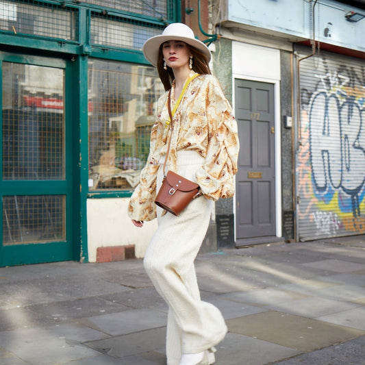Close-up of the exquisite matching colour cable stitching and sleek silver nickel buckle of the pastel cream leather barrel bag, showcasing superior craftsmanship.