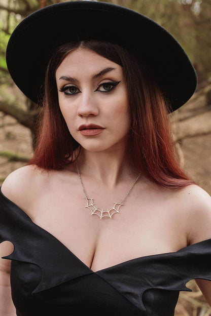 Close-up view of the exquisite bat motif on a Gothic Glam off-shoulder midi dress, crafted from soft organic cotton-sateen.