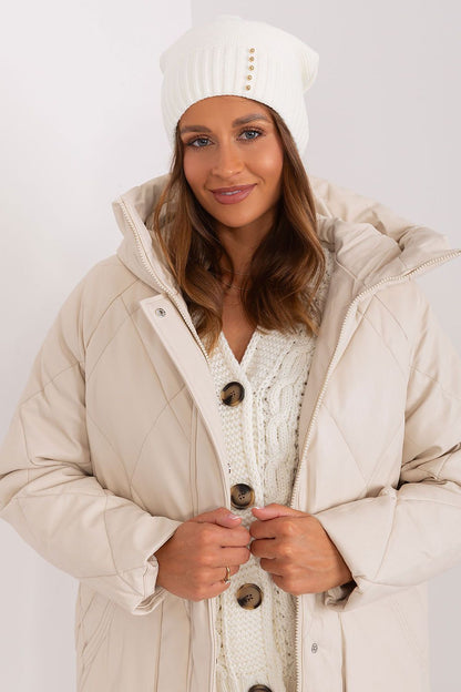 Close-up of Rue Paris women's winter hat showcasing lustrous decorative pearls on a smooth textured fabric.