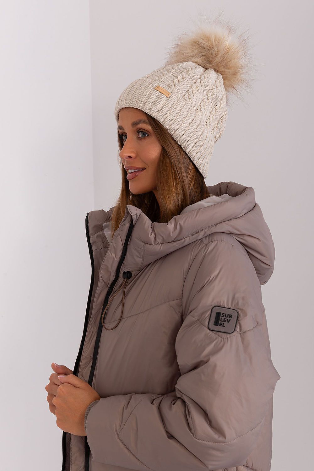 Elegant winter beanie for women by Rue Paris, showcasing a chic plaid pattern and trendy pom-pom, made with high-quality 70% acrylic and 30% wool for warmth.