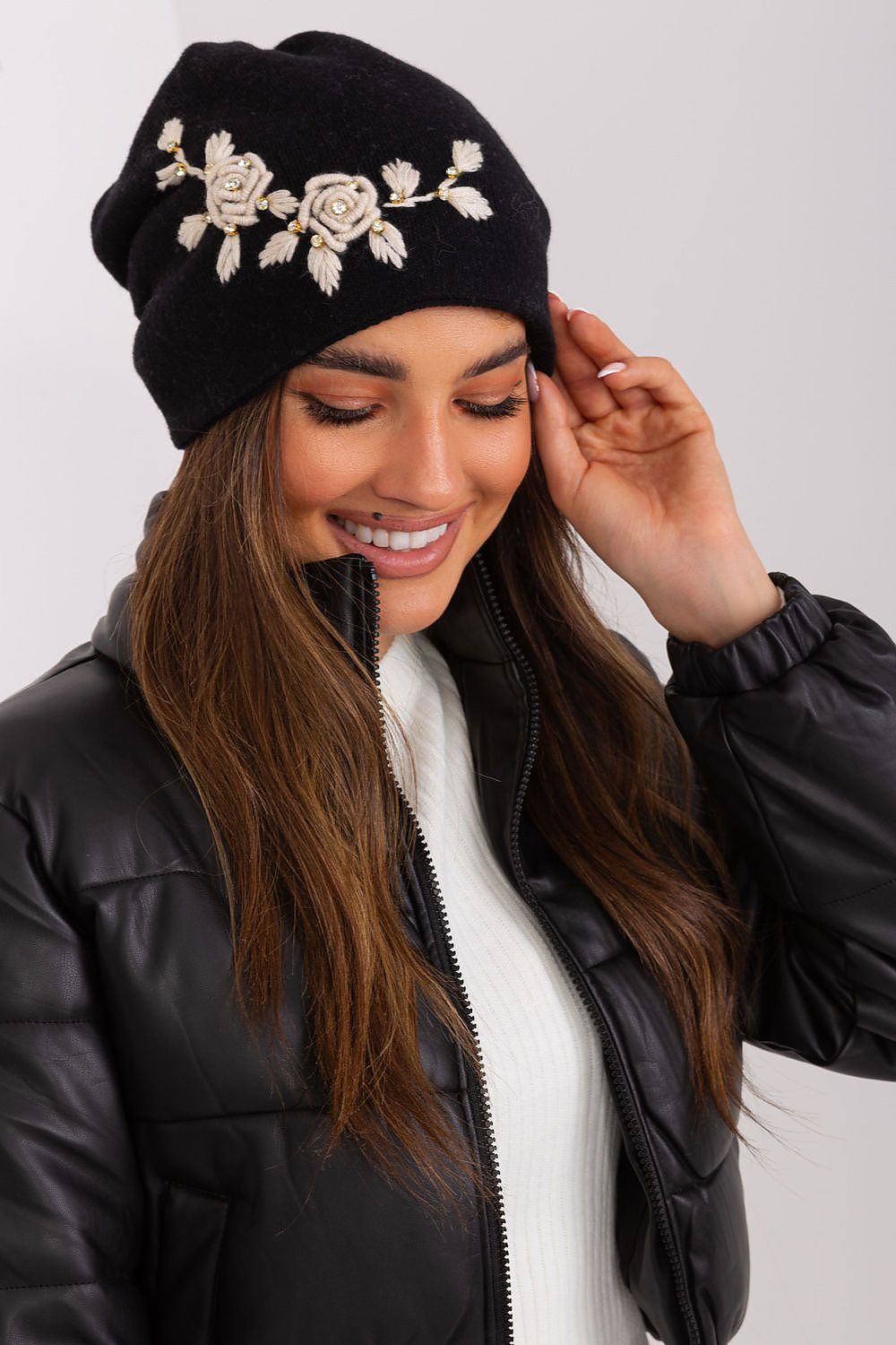 Luxury women's winter hat by AT featuring a smooth knit design and decorative applique, made from a blend of acrylic, cotton, and cashmere.