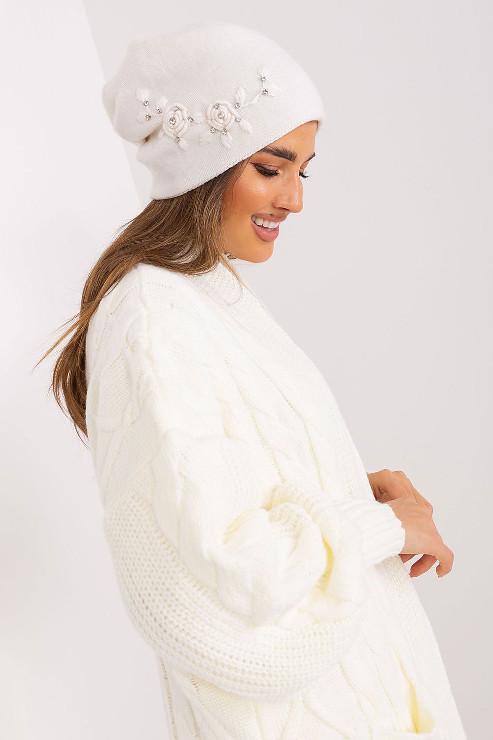 Luxury women's winter hat from AT, featuring smooth knit fabric and elegant decorative applique for a sophisticated style.