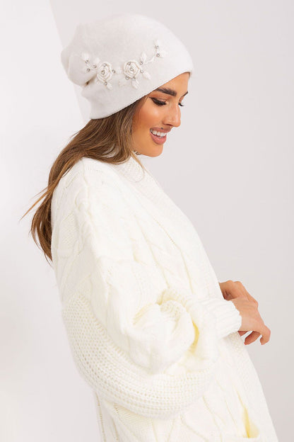 Luxury women's winter hat from AT, featuring smooth knit fabric and elegant decorative applique for a sophisticated style.