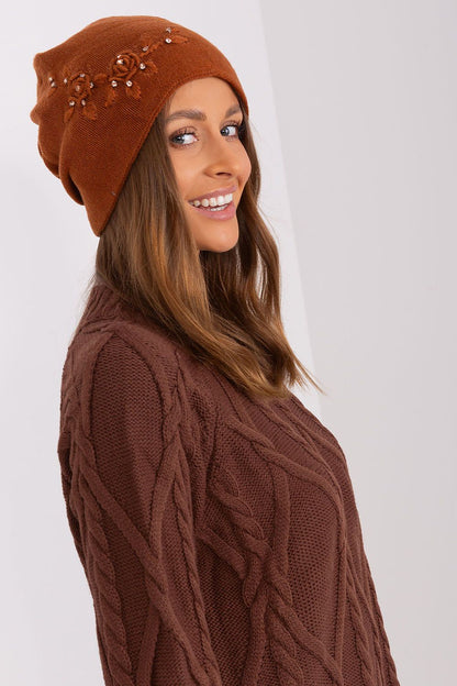 Luxury women's winter hat by AT in smooth knit fabric featuring a decorative applique, designed for warmth and style.