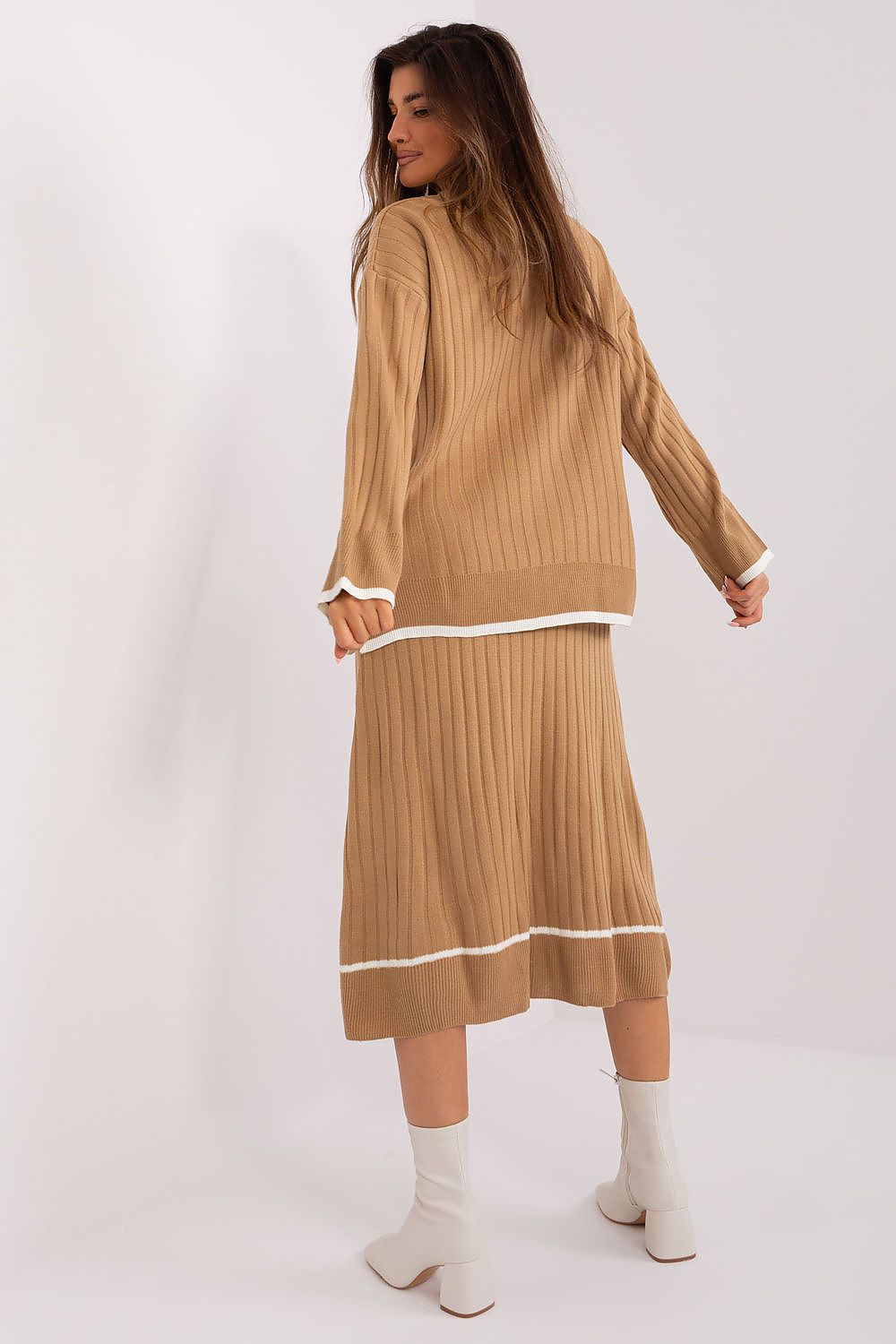 Elegant luxury Badu knitted set featuring a stylish midi-length sweater with contrasting coloured sleeves, paired with a fashionable skirt emphasizing the waist with a decorative belt.