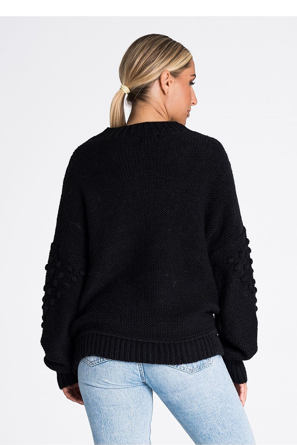 Close-up of the Figl long sleeve sweater showcasing intricate ribbed detailing and charming pom-poms, made from a soft acrylic and nylon blend for ultimate comfort.