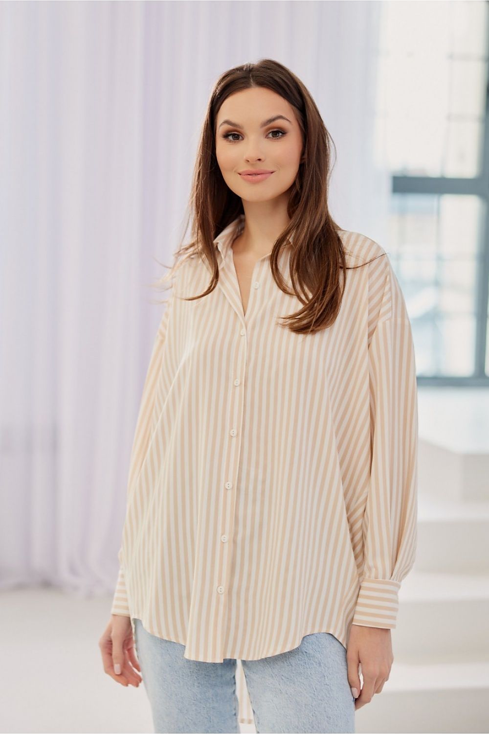 Roco Fashion women's oversized striped shirt featuring an asymmetrical hem and luxurious button adjustable closure, showcasing a sophisticated look.