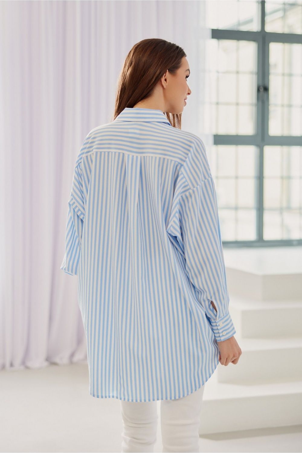 Roco Fashion Women's Oversized Striped Shirt featuring an elegant asymmetrical hem and adjustable button closure, embodying luxury and comfort in chic styling.