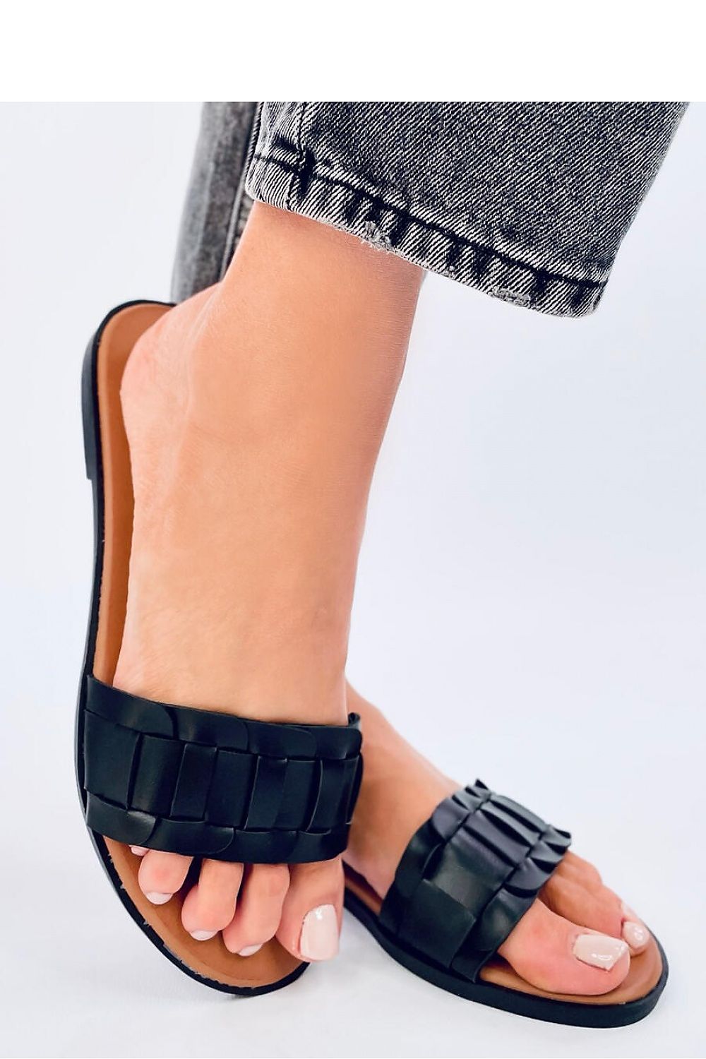 Stylish women's black flip-flops by Inello worn casually, featuring braided straps and an eco-friendly leather finish, ideal for summer fashion.