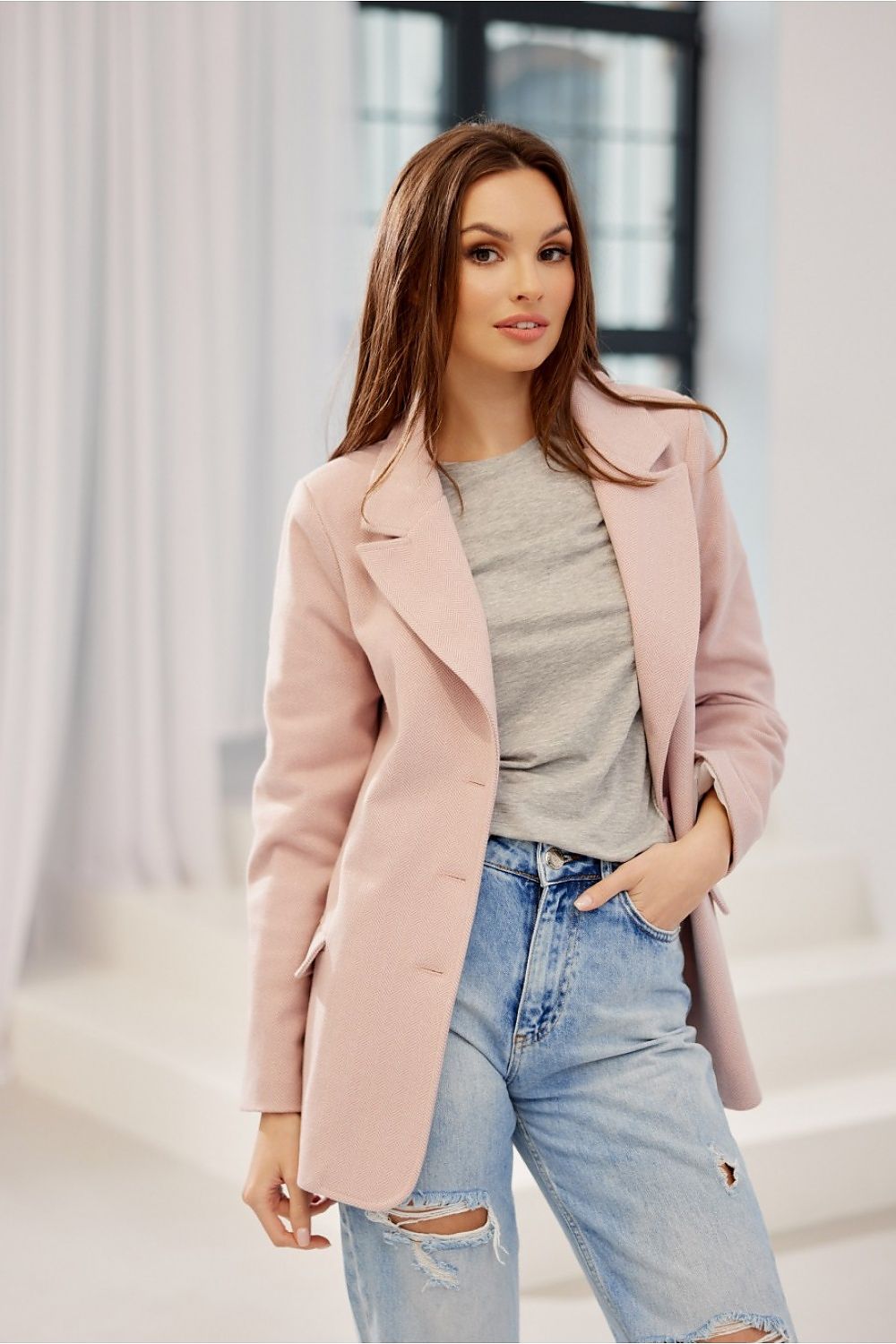 Model elegantly styled in the Freya Classic Blazer Jacket by Roco Fashion in pastel pink, complemented with a grey t-shirt and distressed jeans for a modern twist on sophistication.