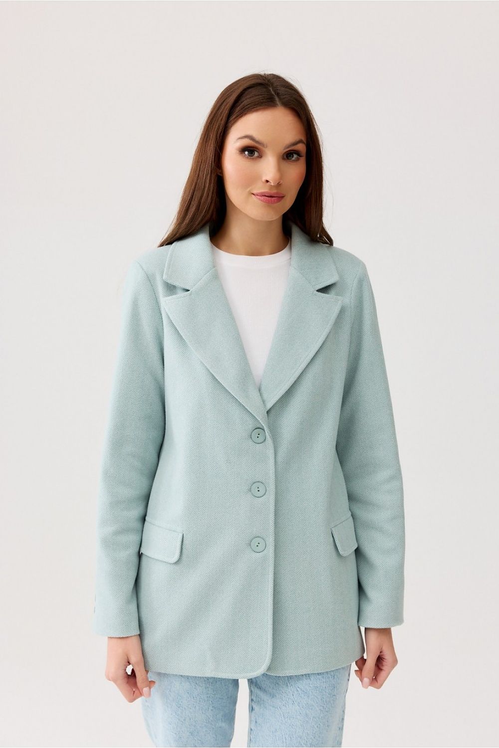 Elegant woman showcasing a light blue Freya Classic Blazer Jacket by Roco Fashion, featuring a sophisticated herringbone design and button closure, perfect for upscale occasions.