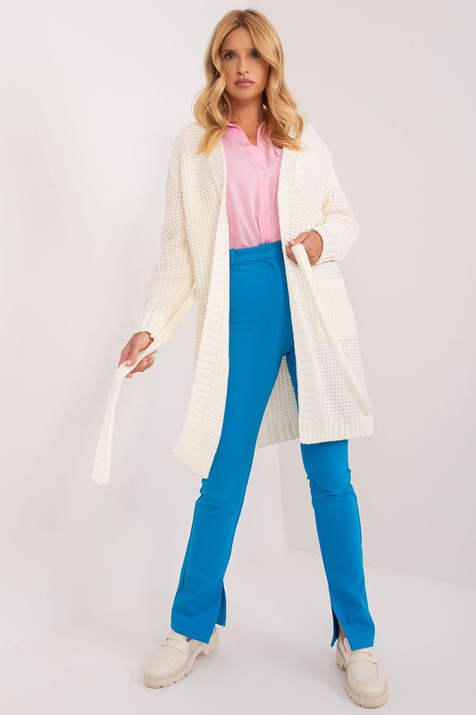 Stylish woman wearing an elegant unbuttoned cardigan with a tie belt from Badu, featuring a sophisticated long length design, paired with vibrant blue trousers and a pink blouse, perfect for a luxurious everyday look.