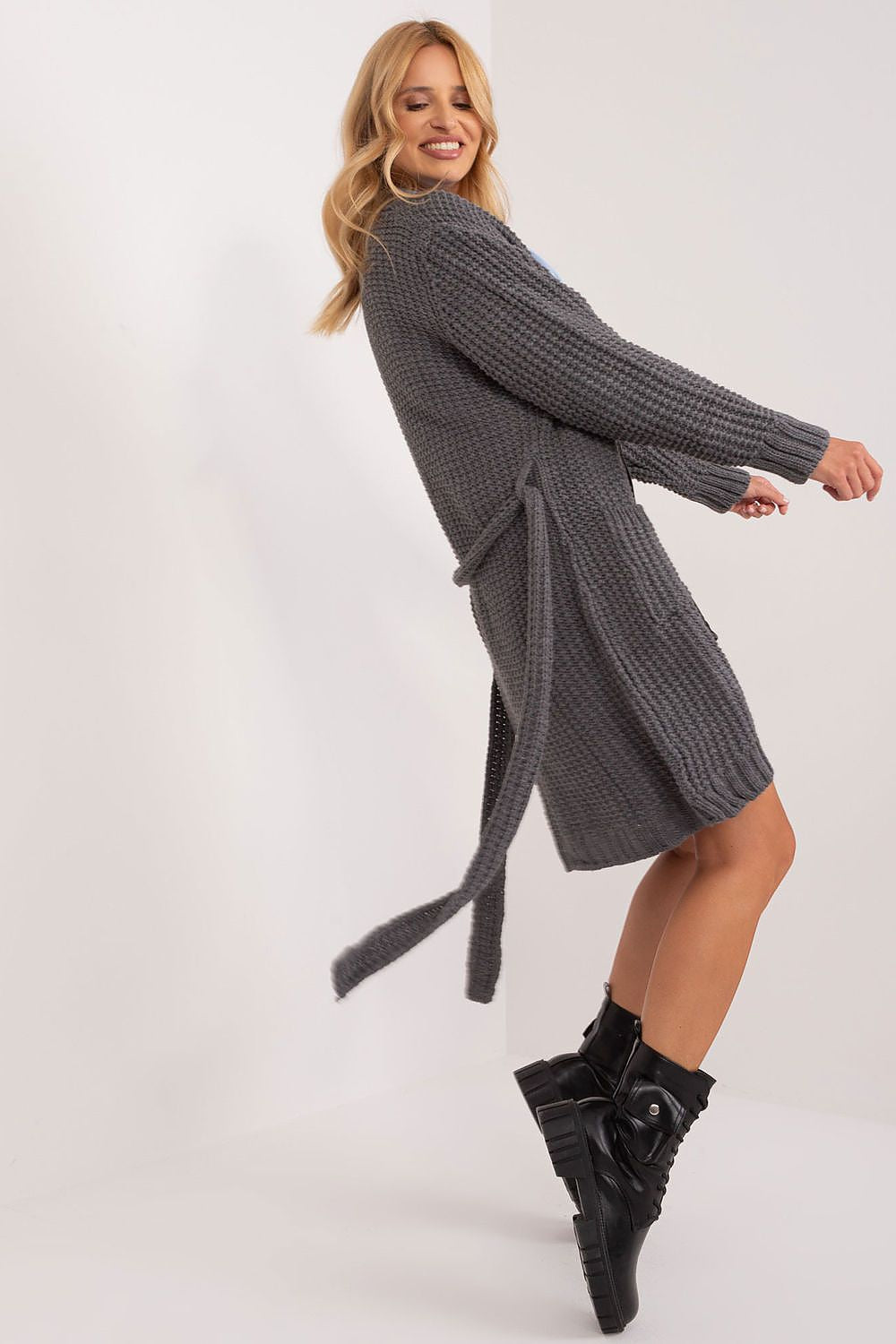 Sophisticated grey unbuttoned cardigan with tie belt by Badu, styled with a playful spin by the model, highlighting its comfort and relaxed fit.
