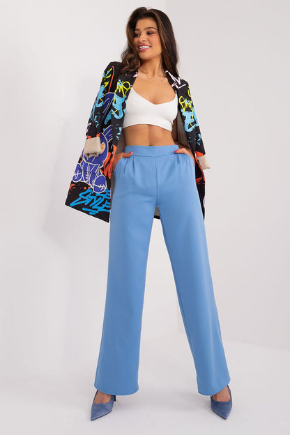 Model exuding confidence in sky blue high waist unbuttoned trousers paired with a chic crop top and vibrant printed jacket, captured by Rue Paris.