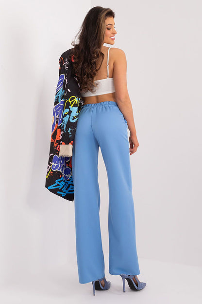 Back view of a model wearing luxurious blue high waist trousers and a trendy graphic jacket, epitomising elegance and modern style by Rue Paris.