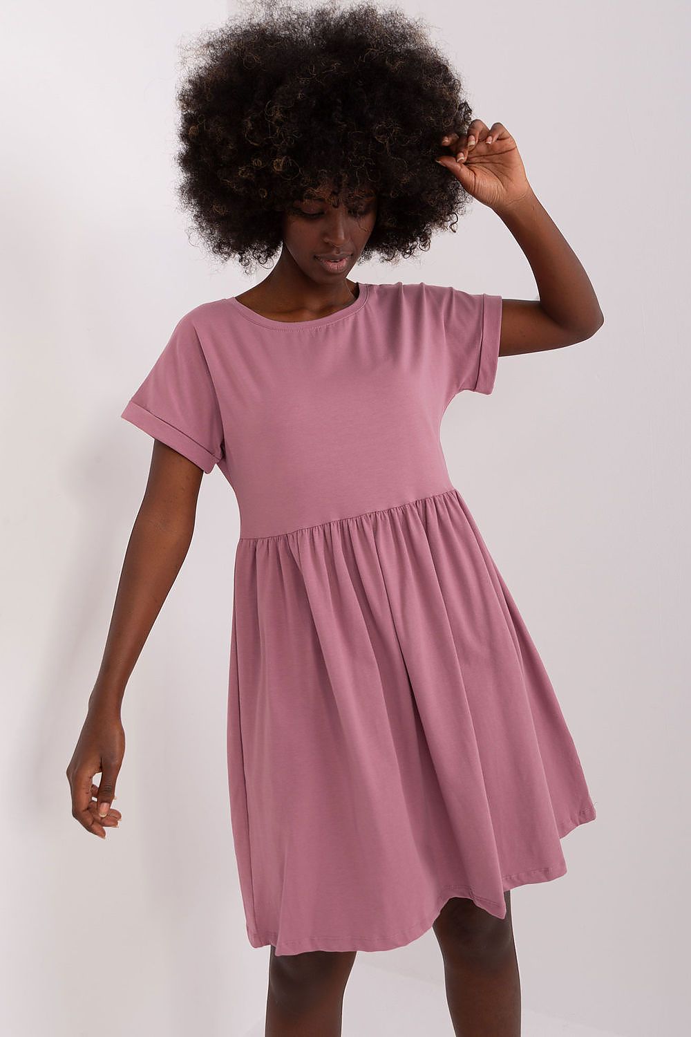 Fashionable woman wearing a Rue Paris flared cotton dress in soft pink, demonstrating its casual charm and feminine silhouette, perfect for any occasion.