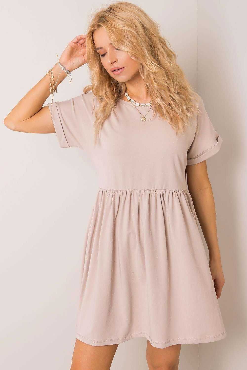 Charming close-up of a woman in a beige flared cotton dress by Rue Paris, highlighting exquisite short sleeves and a graceful silhouette.