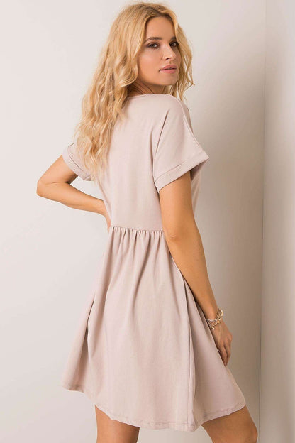 Graceful woman from behind in a beige flared cotton dress by Rue Paris, illustrating an effortless elegance suitable for various occasions.