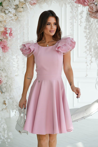 Charming pink cocktail dress by Bicotone with distinctive shoulder ruffles, elegantly cut to enhance the waistline, perfect for special occasions.
