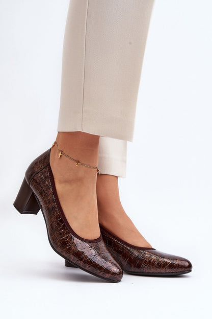 Elegant block heel pumps in rich brown with a glossy finish, featuring an almond toe design and natural leather insole. Worn elegantly by a model, showcasing the perfect blend of comfort and style from Step in Style.