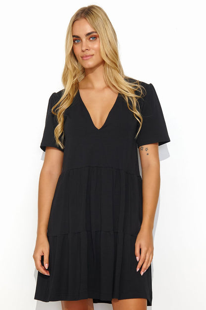 Chic black summer daydress by Makadamia, designed with a stylish v-neck and short sleeves, highlighted by a classic tiered silhouette and elegant back gold detail.