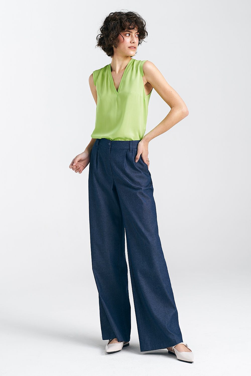 Chic women's wide leg trousers by Nife paired with a vibrant green top, highlighting the flattering silhouette and luxurious design of the high waist trousers.